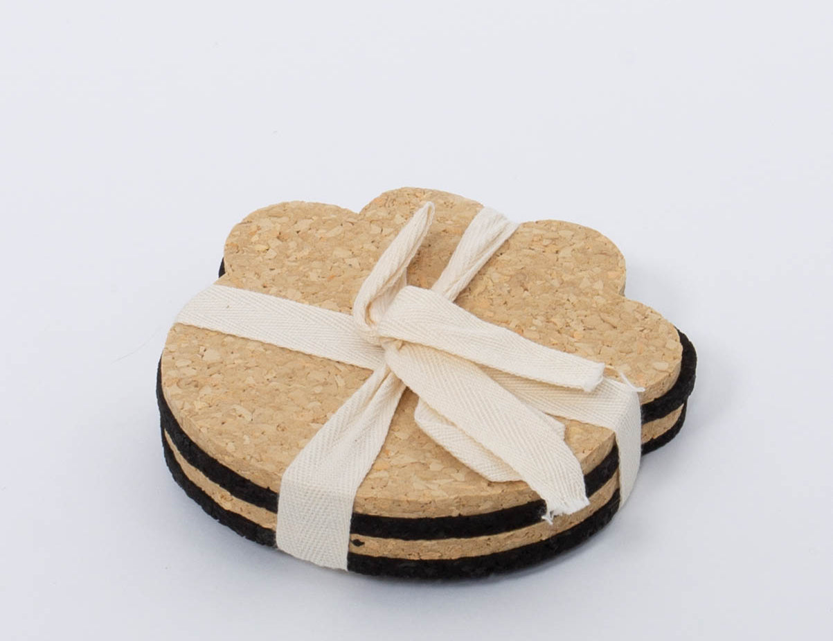 100% Recycled Dog Paw Rubber Coaster Set in tan and black by Ore Originals tied together with cream ribbon.