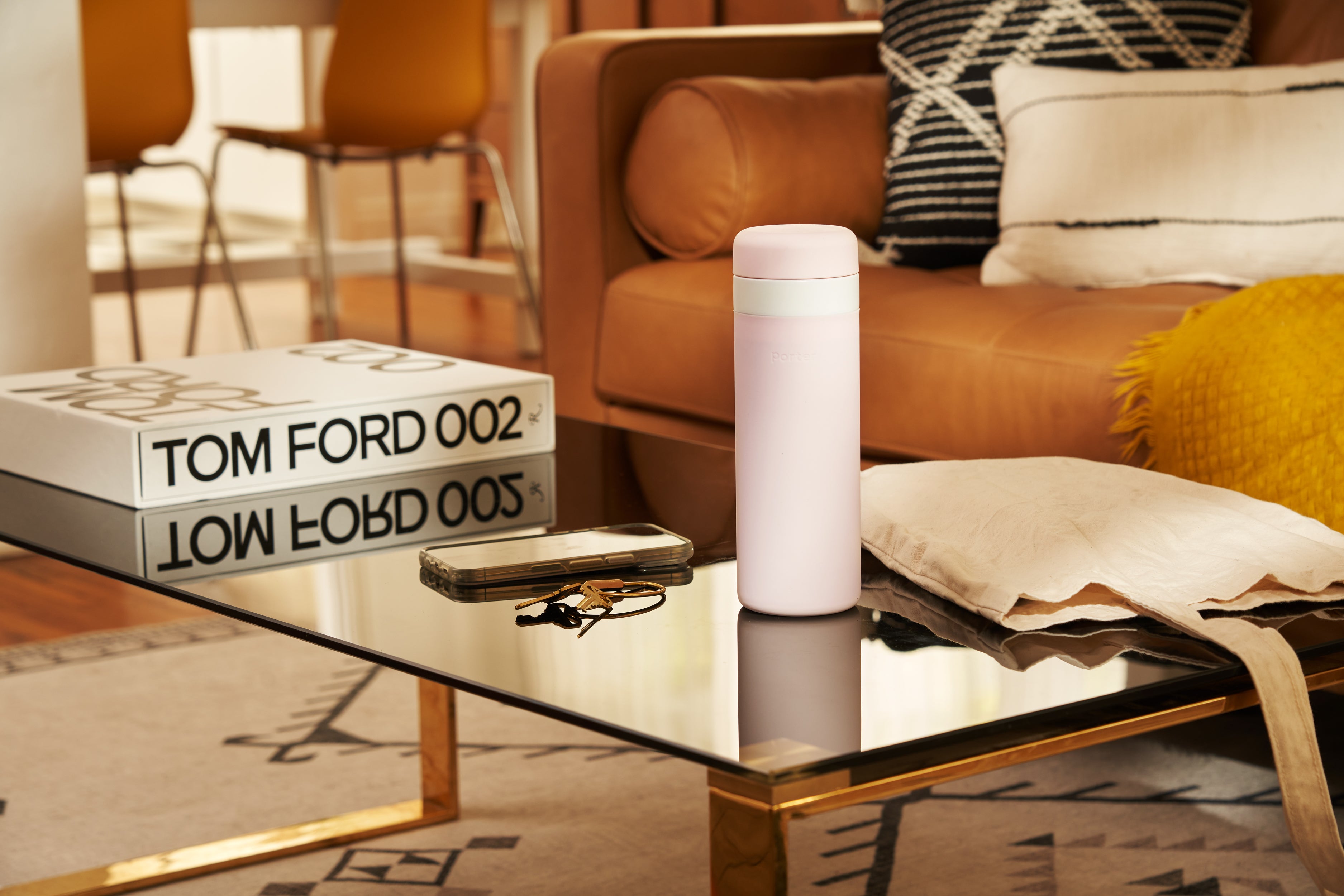 Blush wide mouth ceramic Porter waterbottle on coffee table in luxury living room with TOM FORD book, phone, keys, and bag. 