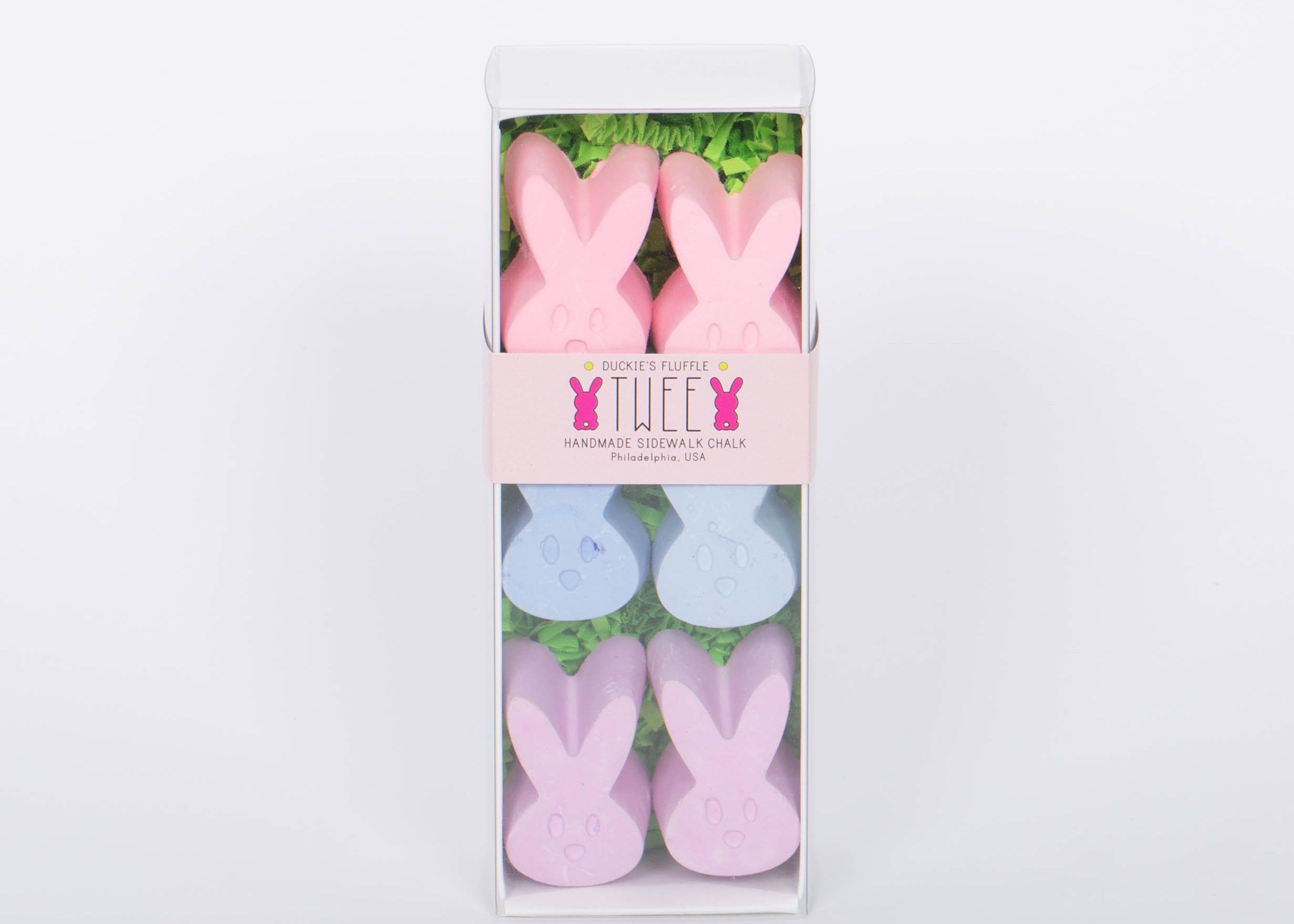 Box of TWEE six piece children's bunny shaped pink, blue, and purple chalk. White background.