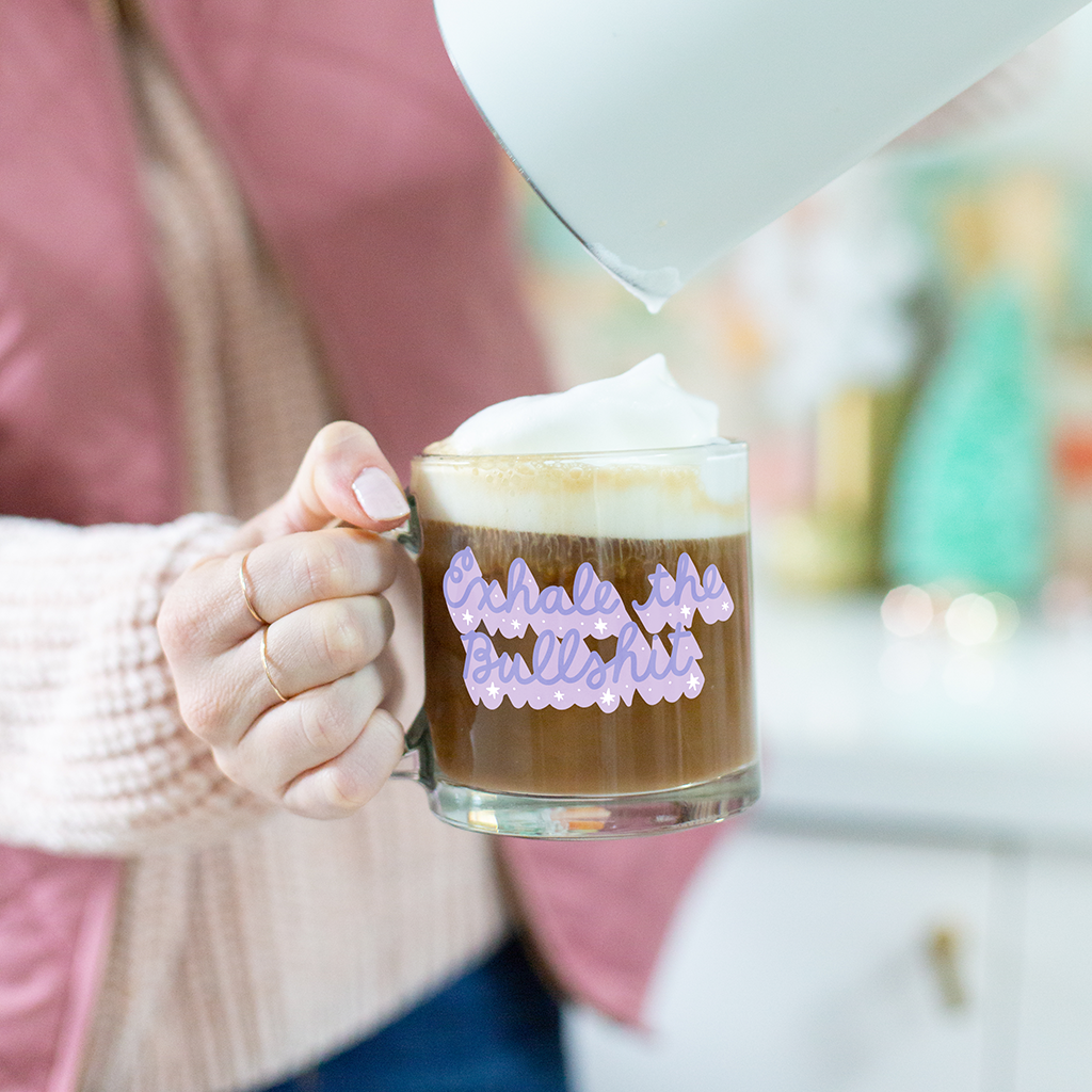 Woman holding "Exhale the Bullshit Mug" with frothy coffee. 