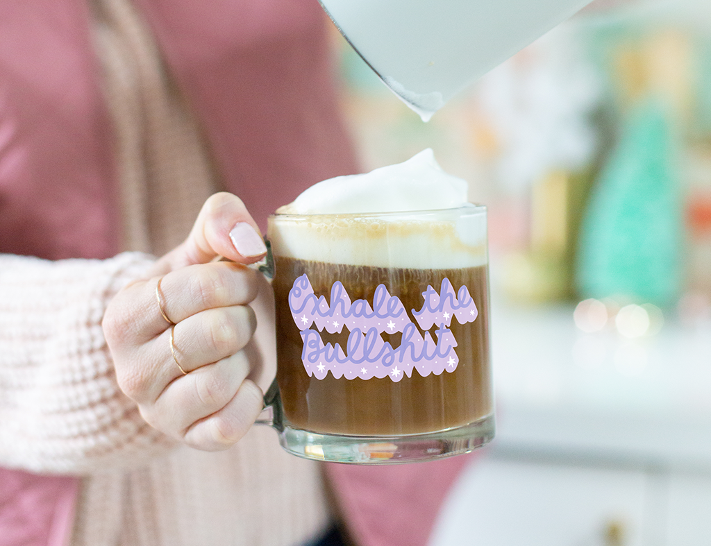 Woman holding "Exhale the Bullshit Mug" with frothy coffee. 