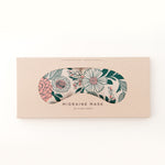 Migraine Mask by Slow North. Strap free cotton weighted eye pillow to be used hot or cold to sooth headaches and tired eyes. Tan and pink and green floral pattern. Inside box. White background.