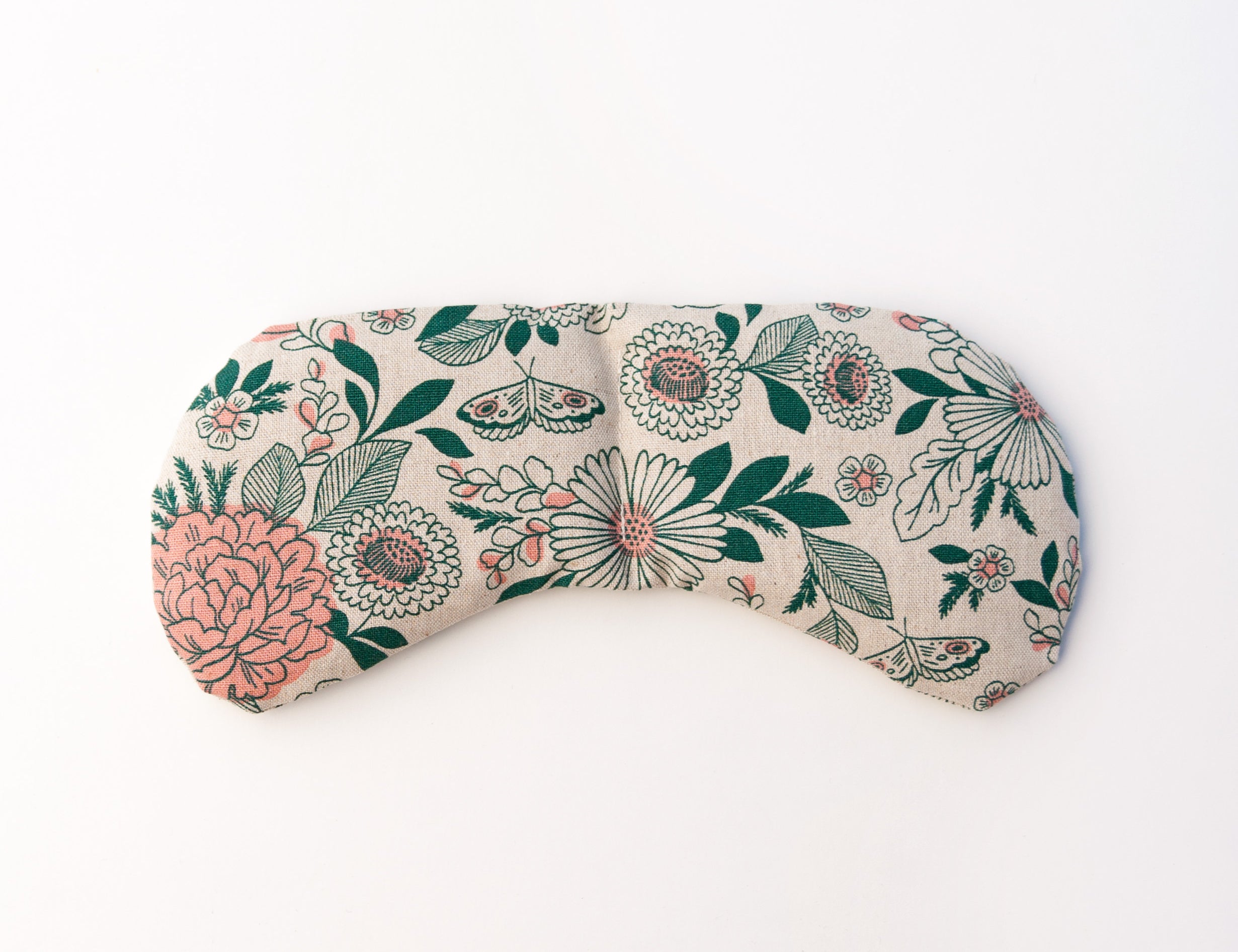 Migraine Mask by Slow North. Strap free cotton weighted eye pillow to be used hot or cold to sooth headaches and tired eyes. Tan and pink and green floral pattern. White background.