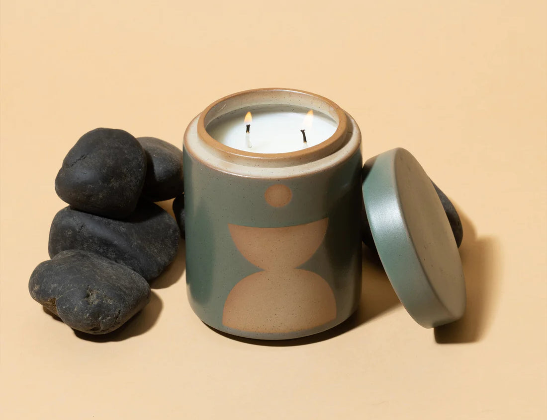 Spanish Moss Candle. Dark green and earth brown. Ceramic vessel with raw block shape and hole in bottom, serves as a perfect planter after candle is used up. Lid off and beside coal rocks.