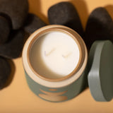 Spanish Moss Candle. Dark green and earth brown. Ceramic vessel with raw block shape and hole in bottom, serves as a perfect planter after candle is used up. Top view of creamy white candles and lid off.