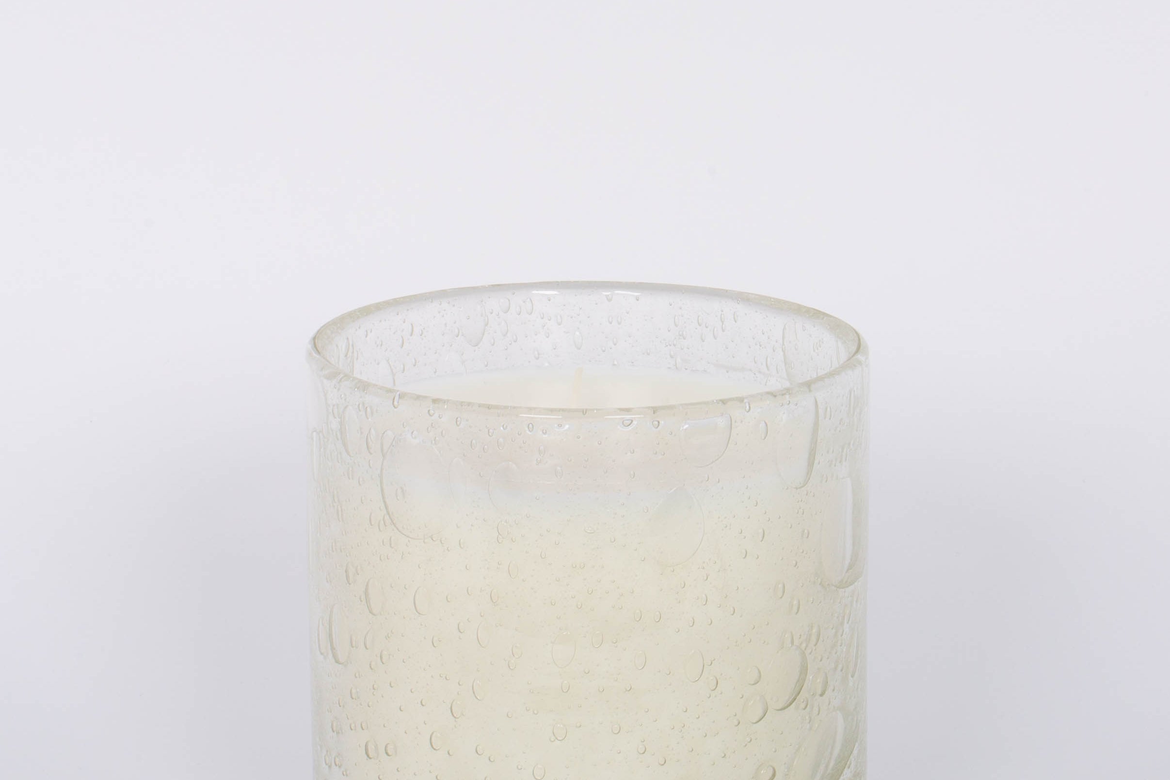 The 42oz clear bubble glass Feve de Tonke Cylindre by Alixx with clove, nutmeg, and cinnamon fragrance and a 200 hour burn time. White background.