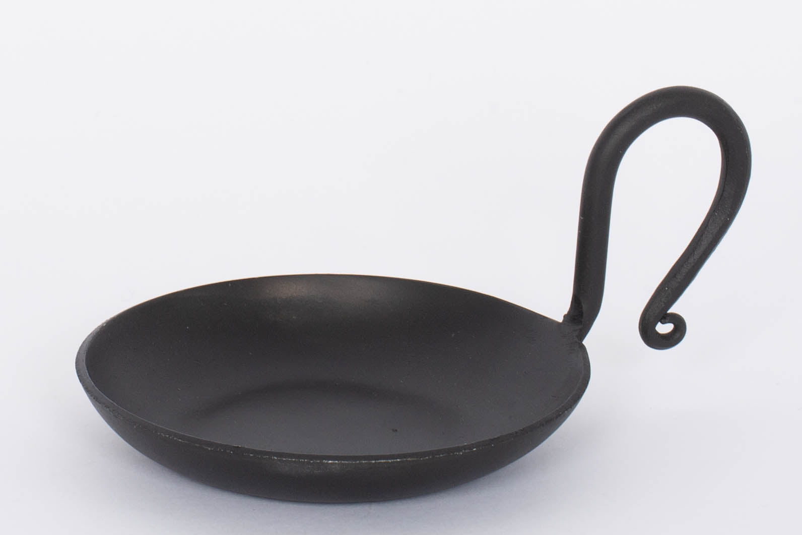 Handmade Forged Cast Iron Serving Dish with black matte finish and thin curving handle.  White background.