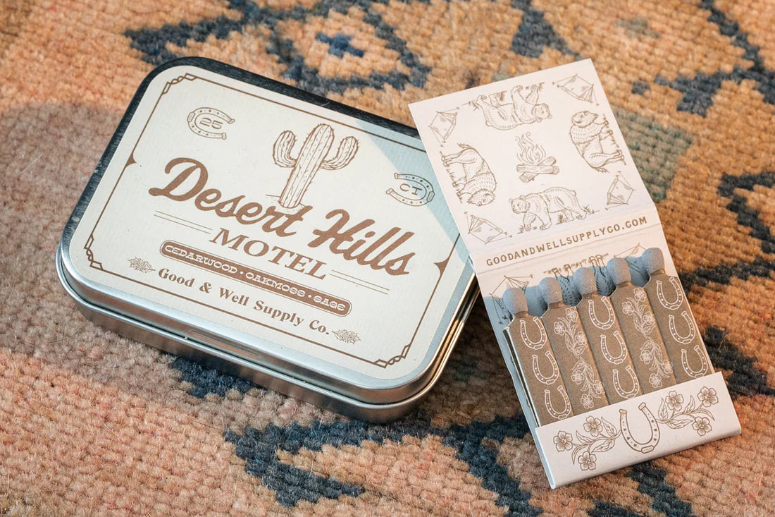 Desert Hills Motel Incense and vintage inspired motel matchbook by Good & Well Supply Co in tan and brown design resting on Southwestern patterned rug. 