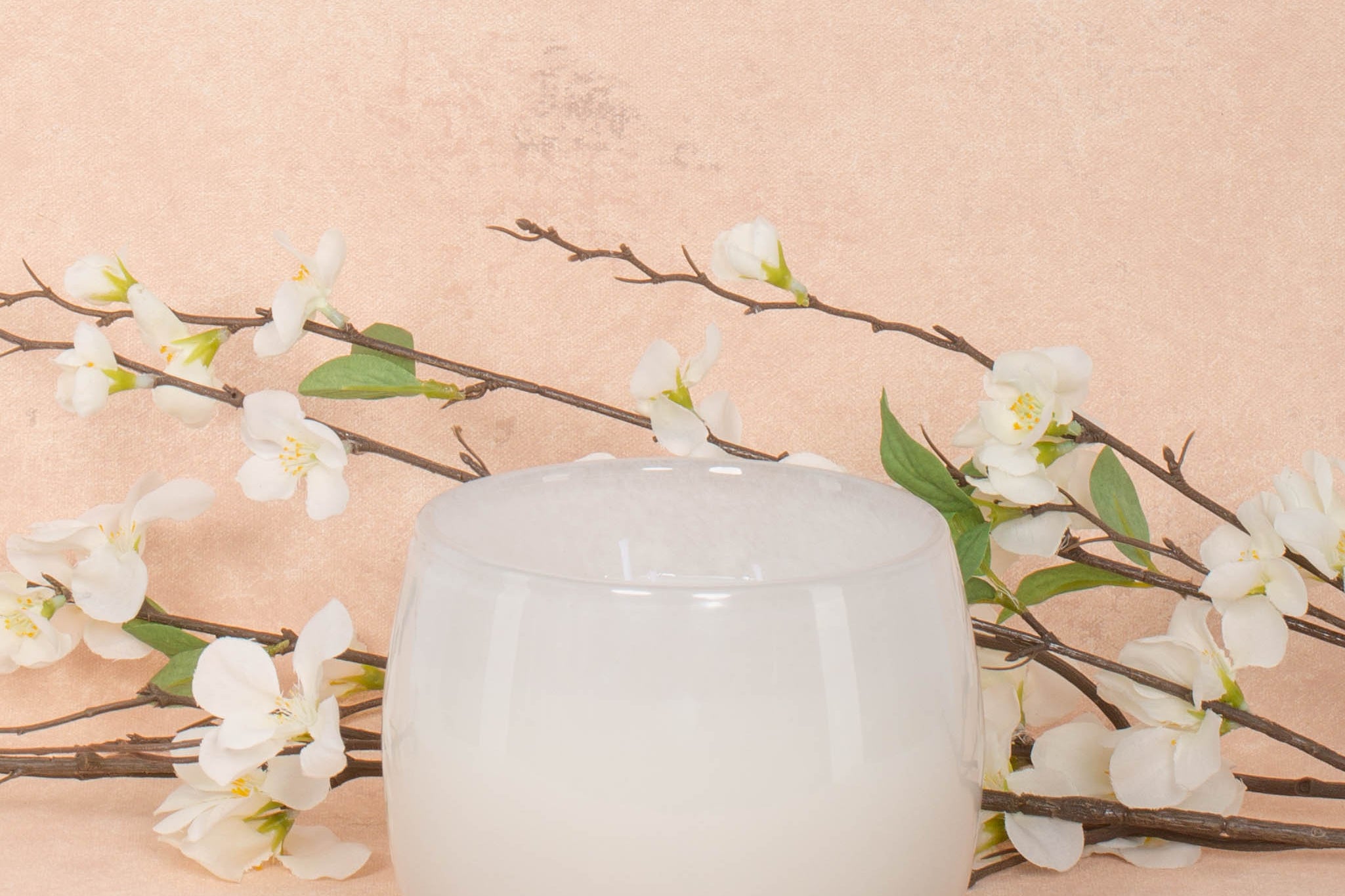 16oz Heure du Thé Ballon candle by Alixx in white. Lily of the valley, water cedar, and musk fragrance. White flowers and pink background behind.