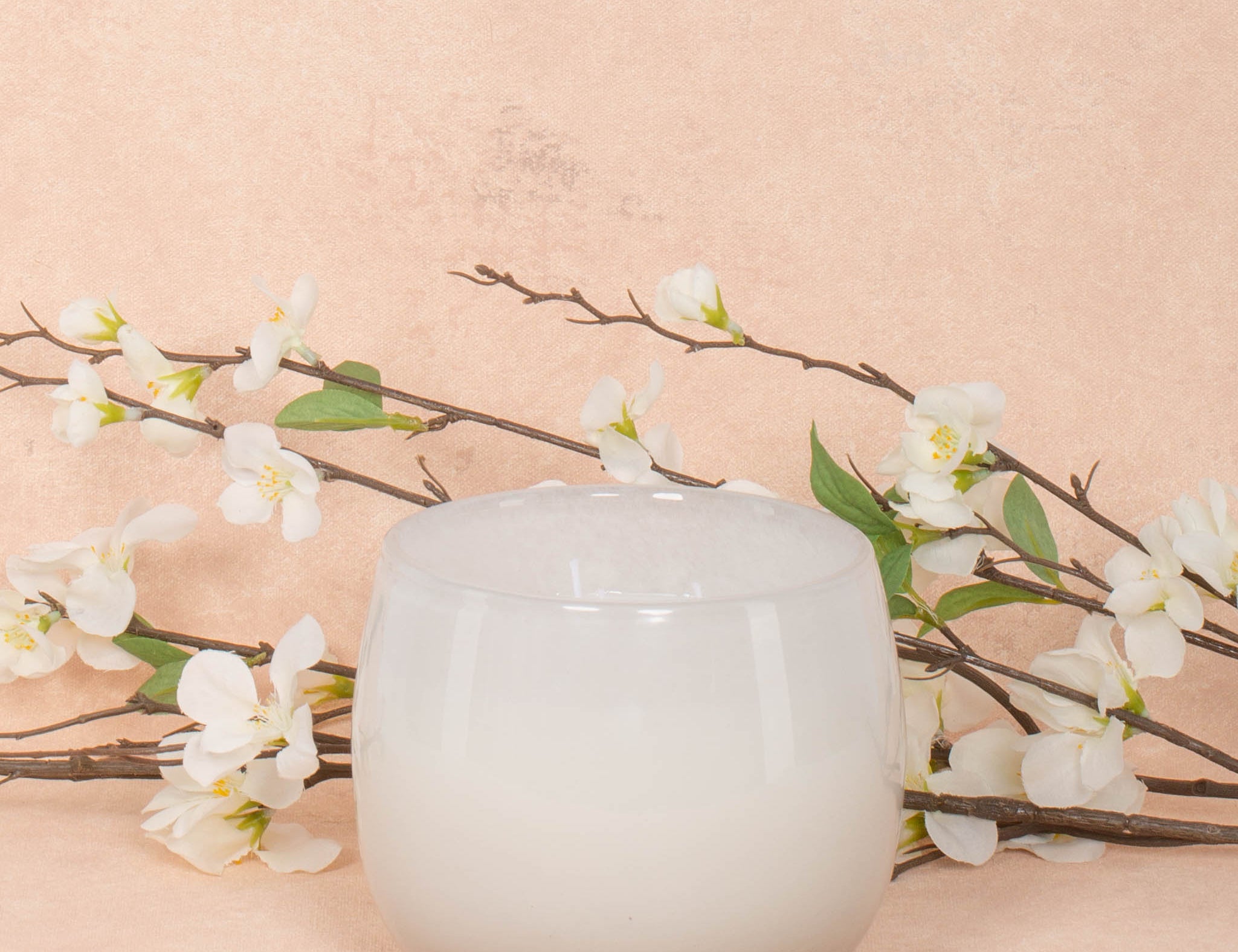 16oz Heure du Thé Ballon candle by Alixx in white. Lily of the valley, water cedar, and musk fragrance. White flowers and pink background behind.