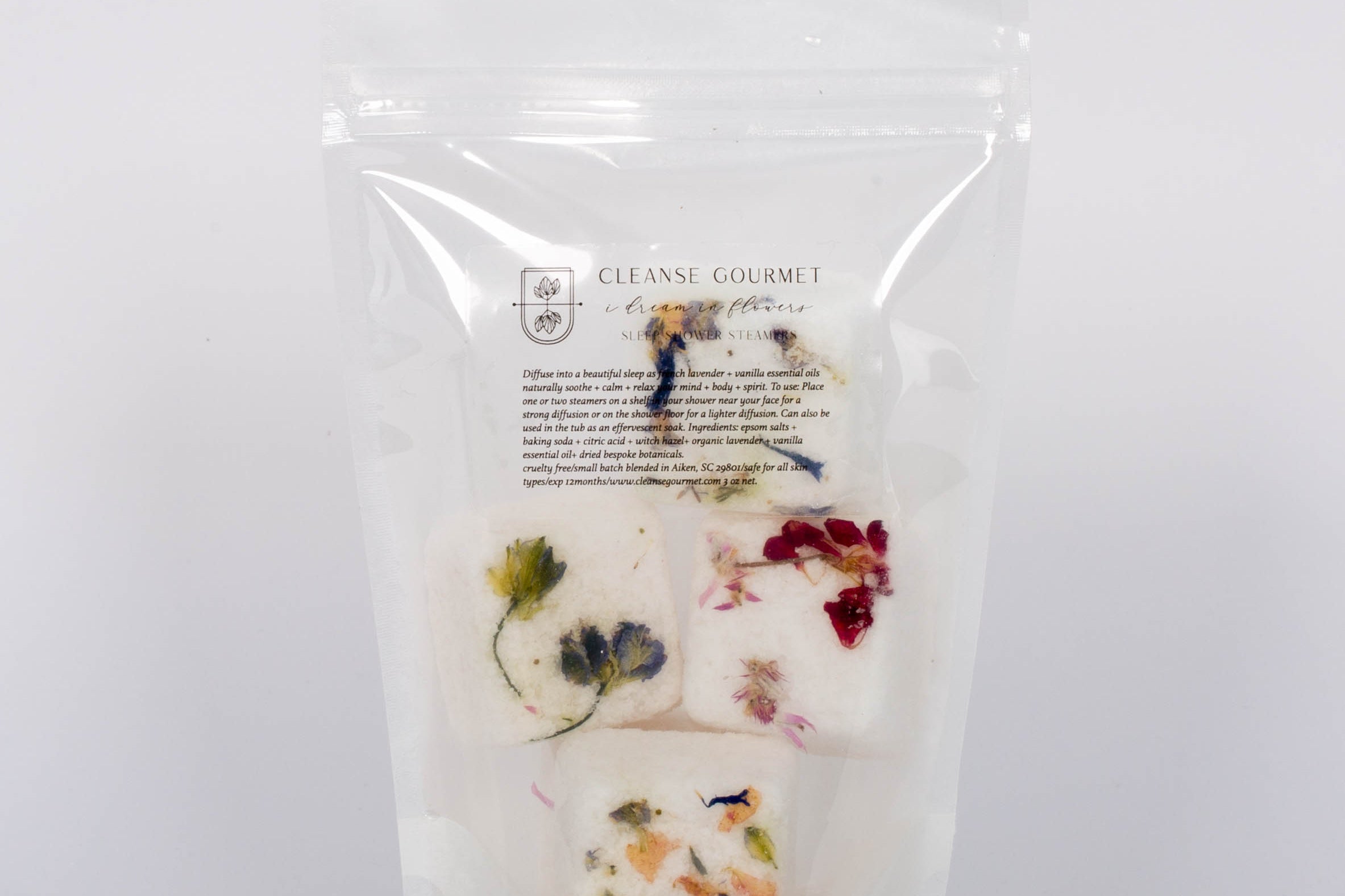 I Dream in Flowers Botanical Shower Steamers by Cleanse Gourmet with French lavender and vanilla essential oils. Four white and floral cubes in clear packaging in front of white background.