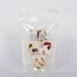 I Dream in Flowers Botanical Shower Steamers by Cleanse Gourmet with French lavender and vanilla essential oils. Four white and floral cubes in clear packaging in front of white background.