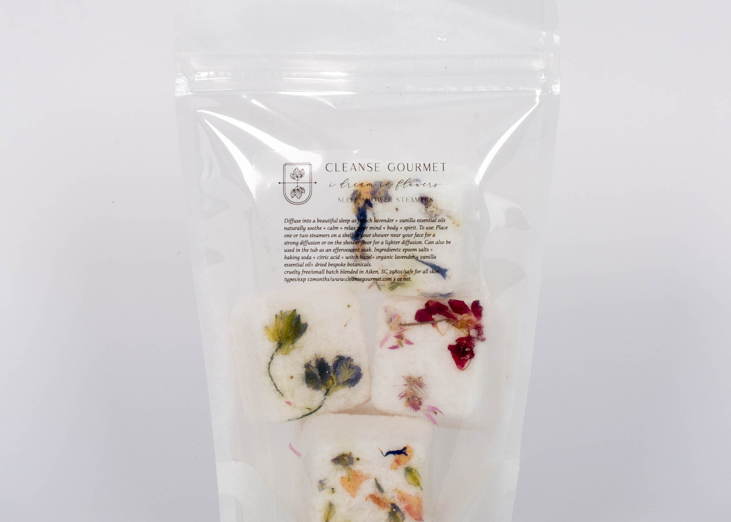 I Dream in Flowers Botanical Shower Steamers by Cleanse Gourmet with French lavender and vanilla essential oils. Four white and floral cubes in clear packaging in front of white background.