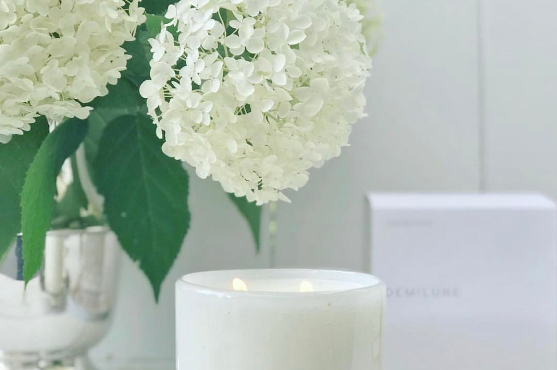 Fleur Blanche Cylindre white bubble glass candle by Alixx with moonflower and violet aroma. Hydrangeas bouquet and white interior setting. 