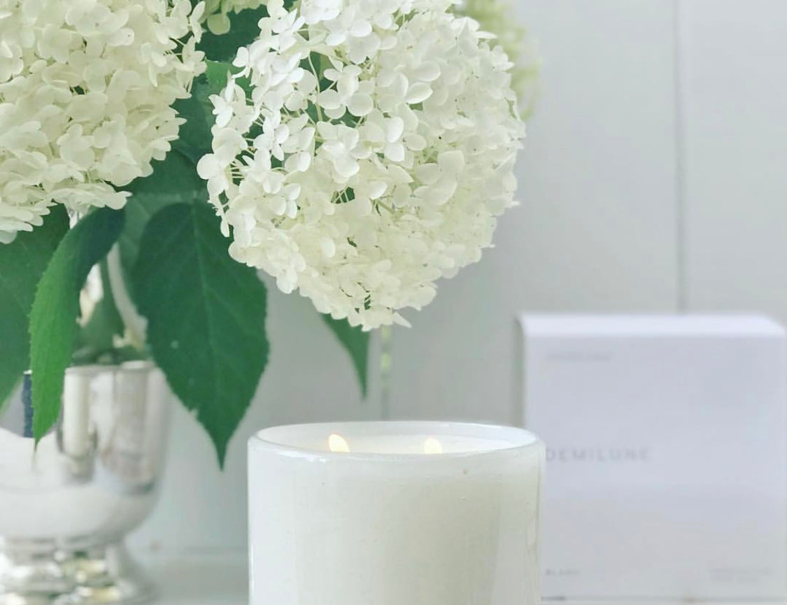 Fleur Blanche Cylindre white bubble glass candle by Alixx with moonflower and violet aroma. Hydrangeas bouquet and white interior setting. 