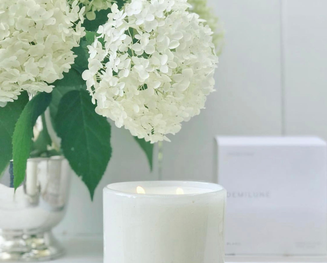 Fleur Blanche Cylindre white bubble glass candle by Alixx with moonflower and violet aroma. Hydrangeas bouquet and white interior setting. 