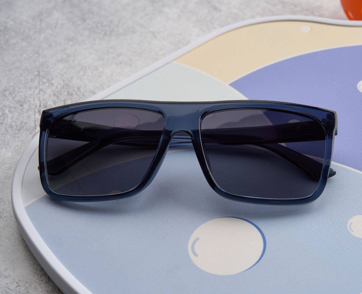 Blue sunglasses on a colorful circular object