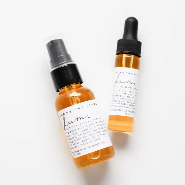 Two amber glass dropper and spray bottles with white labels, photographed on a clean white background. The label text appears to read 'Among the Flowers' and 'lumi'.