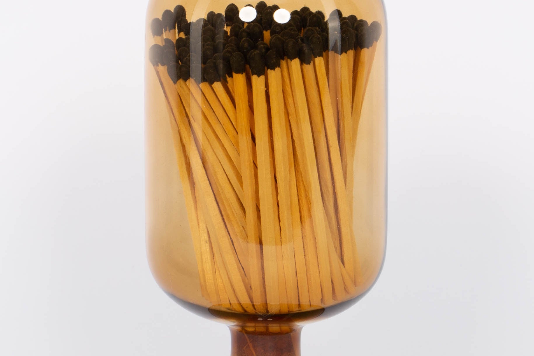 Amber Match Cloche by Skeem in jewel-toned vintage glass domes fitted with cork, holding 120 matches. White background.