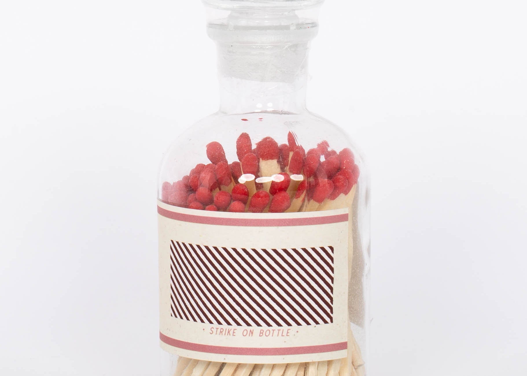 Red Safety Matches by Paddywax with match striker on back of clear glass bottle and red match tips.