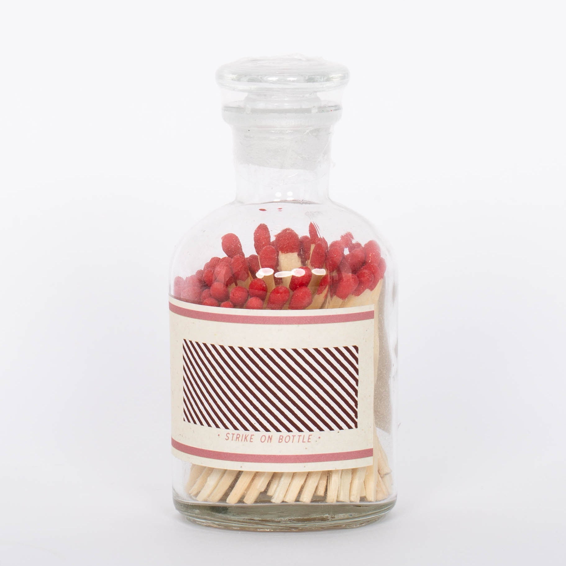 Red Safety Matches by Paddywax with match striker on back of clear glass bottle and red match tips.