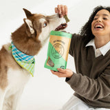 Person feeding a dog a treat from a bag labeled 'Nylabone'