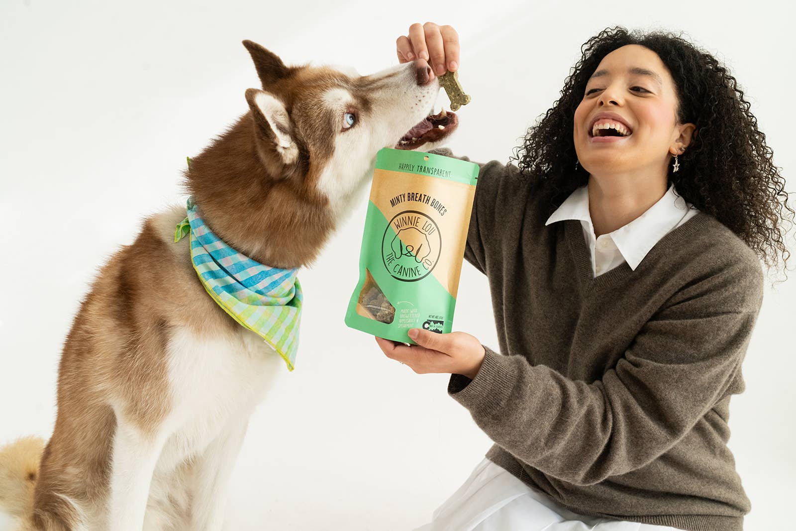 Person feeding a dog a treat from a bag labeled 'Nylabone'