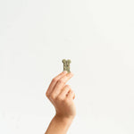Hand holding a small green object against a white background
