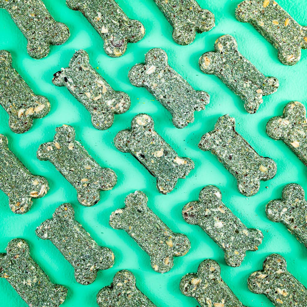 Pattern of green bone-shaped dog treats on a teal background