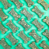 Pattern of green bone-shaped dog treats on a teal background