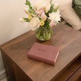 Pink book and vase with flowers on a wooden surface