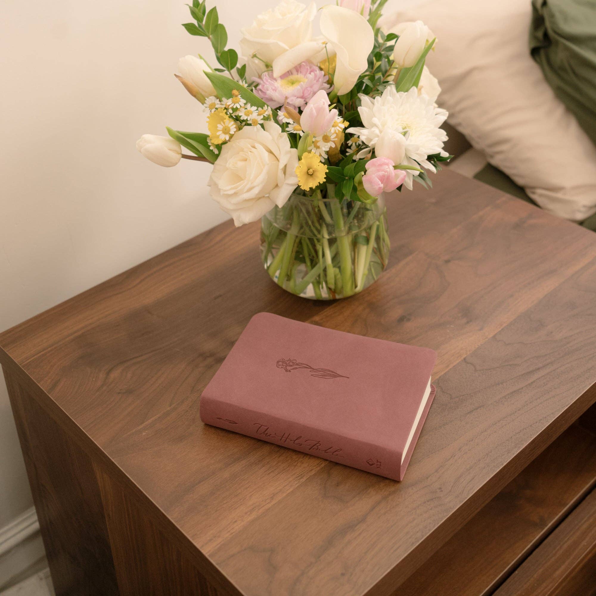 Pink book and vase with flowers on a wooden surface