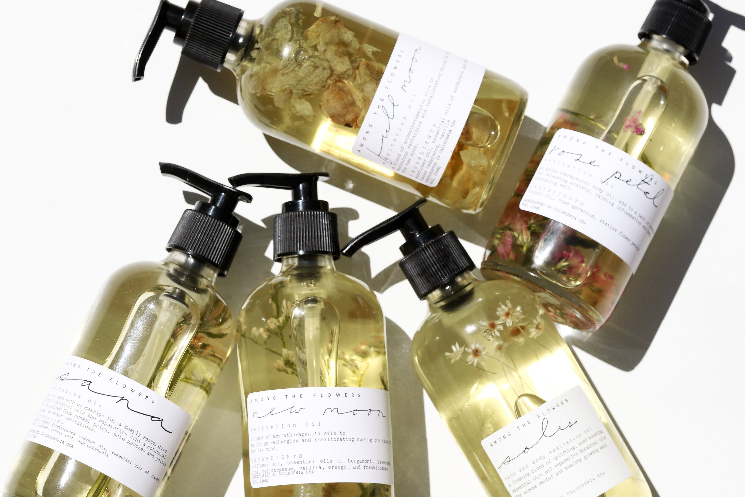 Rose Petal Body Oil and five other premium body oils by Among the Flowers in clear spray bottles. 