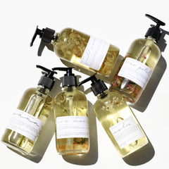 Rose Petal Body Oil and five other premium body oils by Among the Flowers in clear spray bottles. 