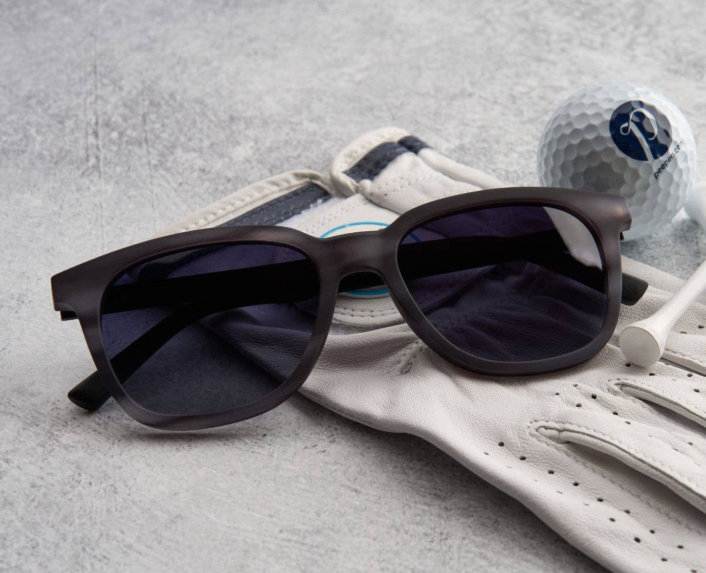 Black sunglasses on a golf glove with a golf ball in the background