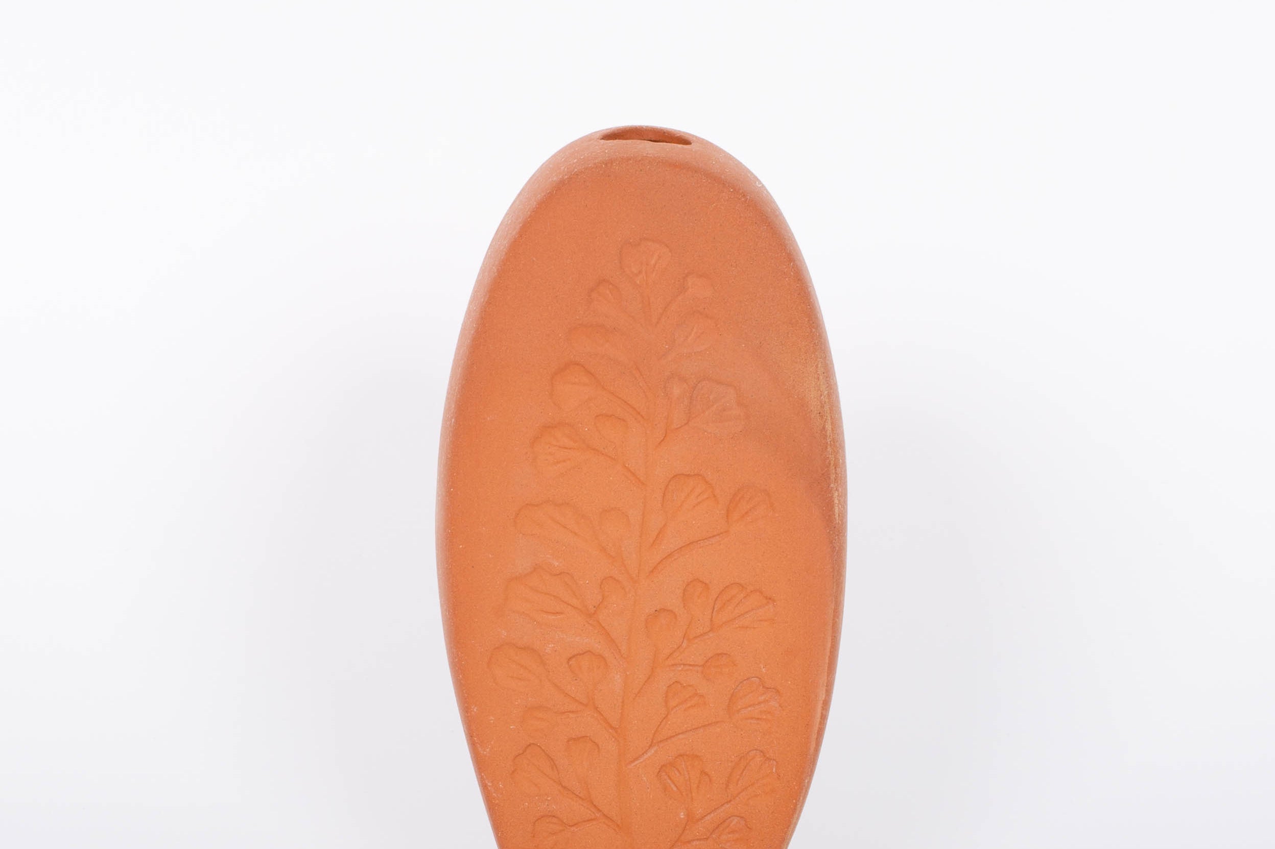 Tall oval Poppy Budvase in terracotta geometric silhouette with imprint of live plant. White background.