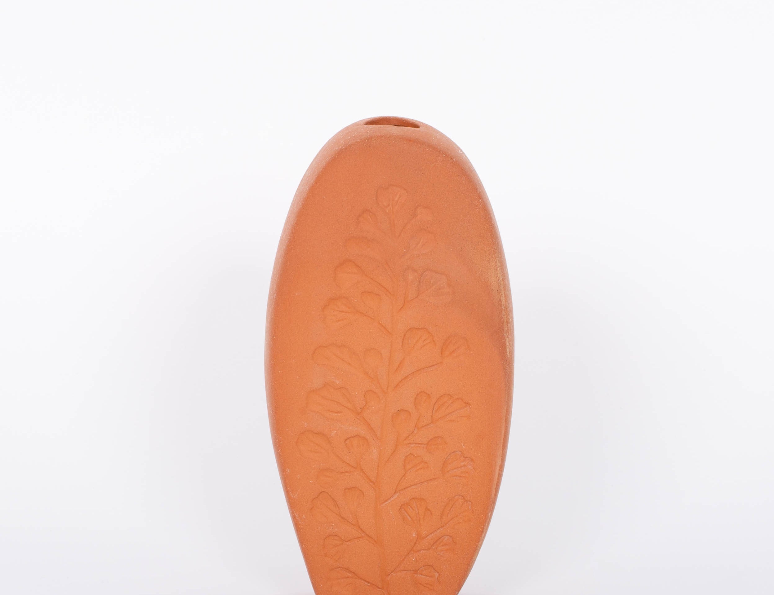 Tall oval Poppy Budvase in terracotta geometric silhouette with imprint of live plant. White background.