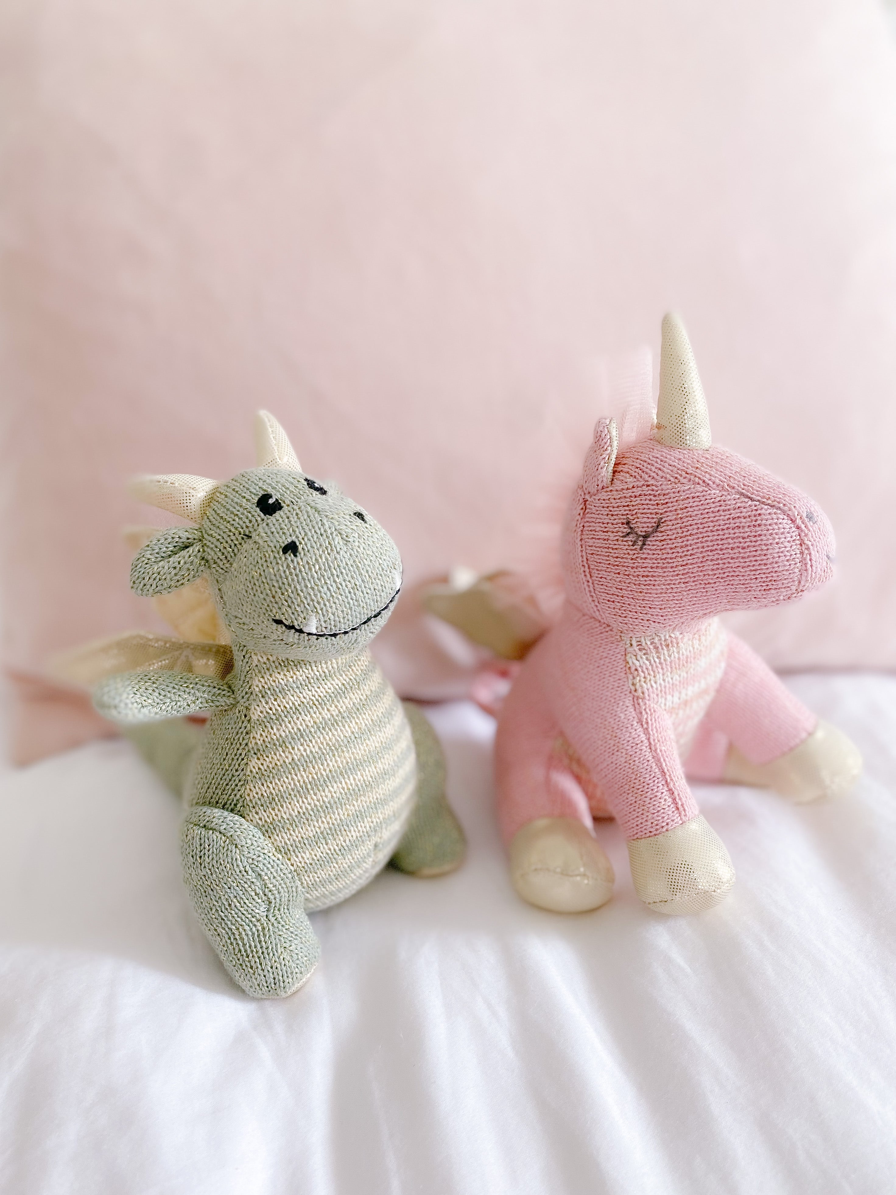 Serenity Unicorn Plush in Pink and Dragon Plush in Green on fluffy white bed