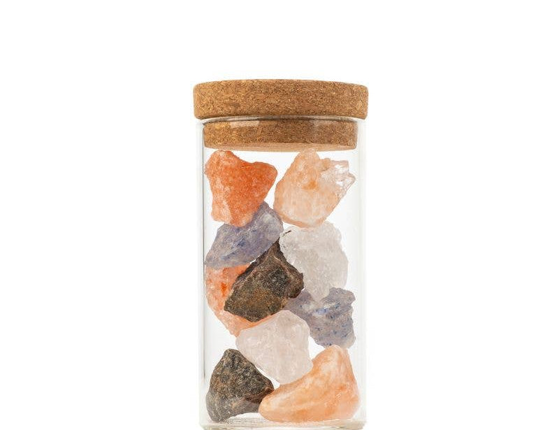 Clear glass jar with cork lid containing multicolored stones on a white background
