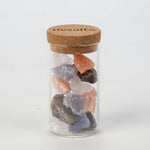 Glass jar with colorful salt crystals and cork lid on a white background