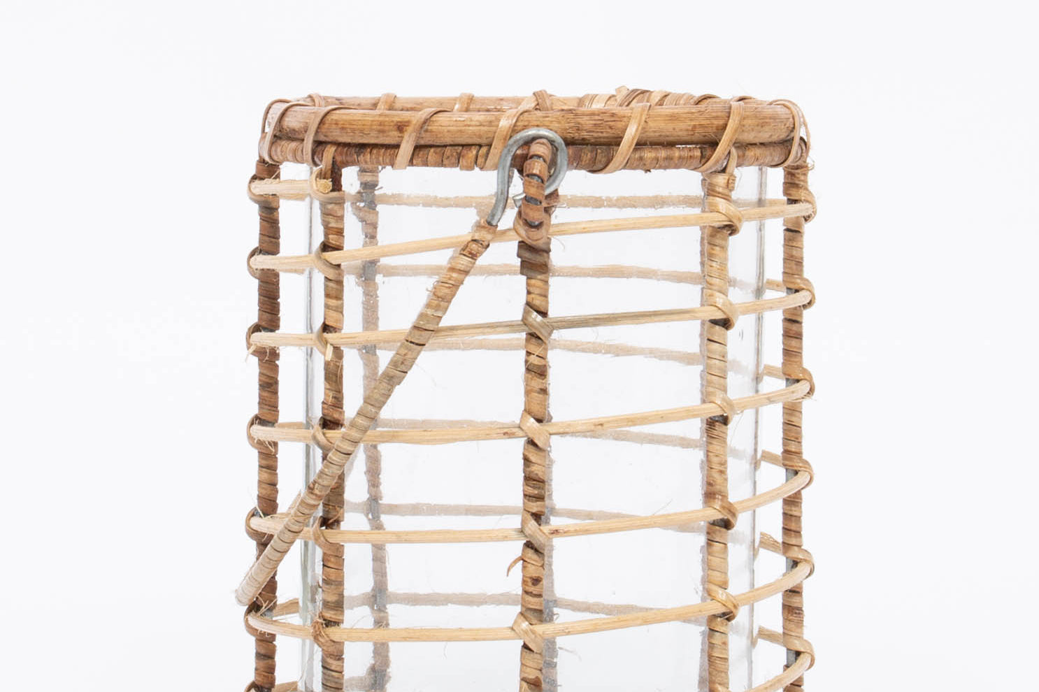 Side view. Glass Lieto Lantern with rattan exterior and handle in natural light wood tone. White background. 