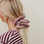Person with a pink striped scrunchie in their hair against a plain background