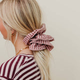 Person with a pink striped scrunchie in their hair against a plain background