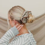 Woman with styled hair and striped sweater against a neutral background