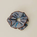 Blue and brown striped scrunchie on a beige background