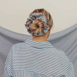 Person wearing a striped shirt with a headscarf on a neutral background