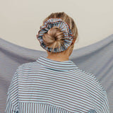 Person wearing a striped shirt with a headscarf on a neutral background
