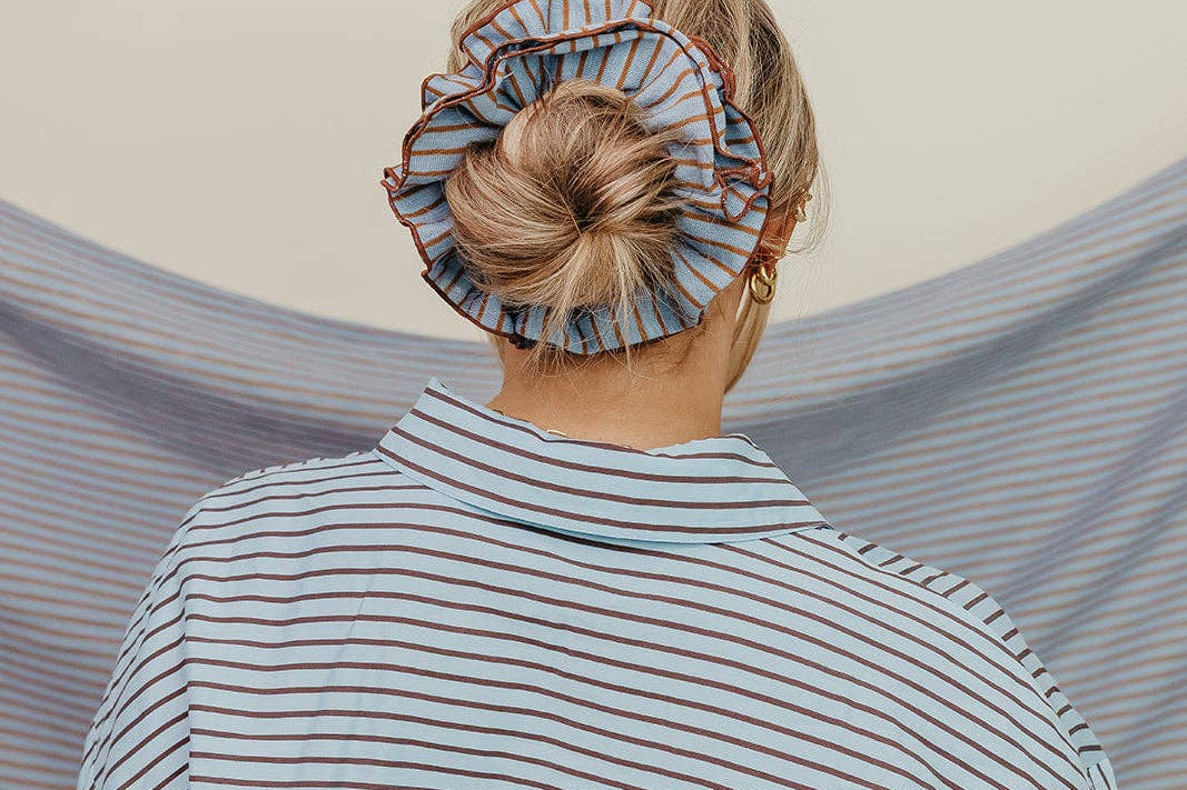 Person wearing a striped shirt with a headscarf on a neutral background