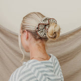 Person with styled hair and a striped shirt against a neutral background