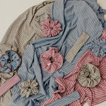 Textile piece with striped fabric and floral embellishments on a neutral background